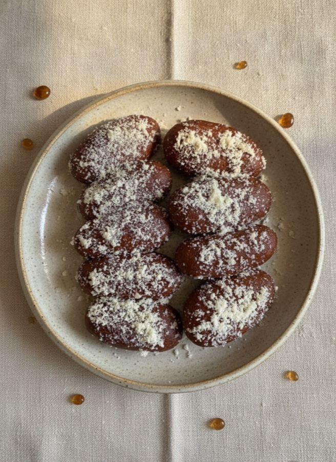 Our kalojam — dark syrup-soaked sweets dusted with khoya, on a ceramic plate